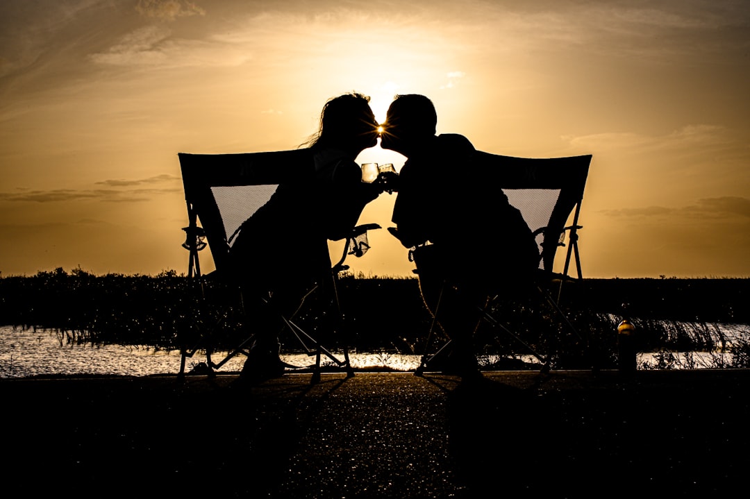 a-couple-of-people-sitting-on-a-bench-with-a-canopy-and-a-sunset-kmod-ihrq2a